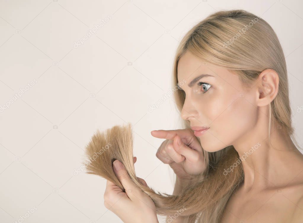Dissatisfaction of a model with her damaged blonde hair ends.
