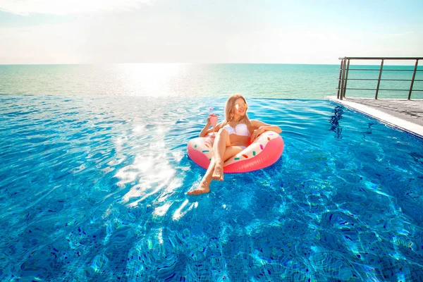 Zomervakantie. Vrouw in bikini op de opblaasbare donut matras in het zwembad van Spa. — Stockfoto