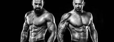 Handsome fit man posing with tattoo and beard. Sport and fashion concept isolated on black background.