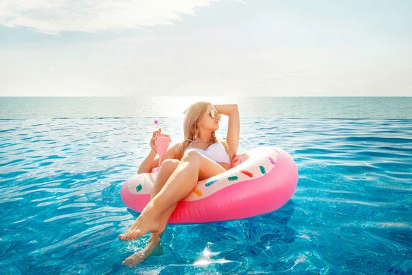 Zomervakantie. Vrouw in bikini op de opblaasbare donut matras in het zwembad van Spa. — Stockfoto
