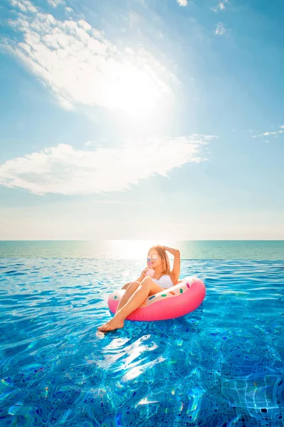 Sommerferien. Frau im Bikini auf der aufblasbaren Donut-Matratze im Wellness-Pool. — Stockfoto