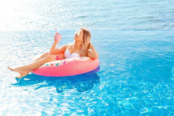 Vacaciones de verano. Mujer en bikini en el colchón inflable de donas en la piscina SPA. Playa en el mar azul . — Foto de Stock