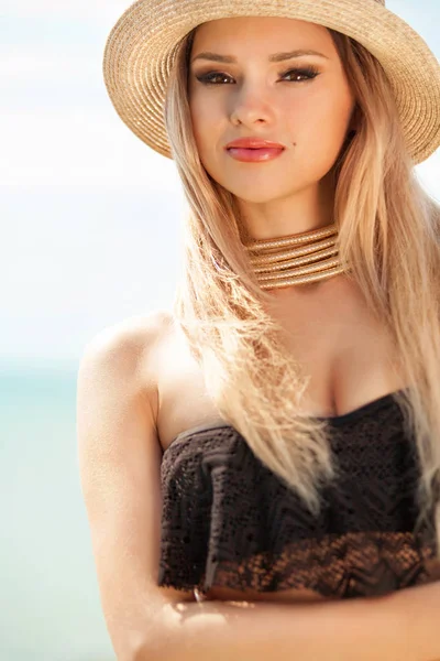 Όμορφη ταιριάζει γυναίκα στο μαύρο μαγιό και καπέλο ποζάρει στην παραλία. Καλοκαιρινές διακοπές. — Φωτογραφία Αρχείου