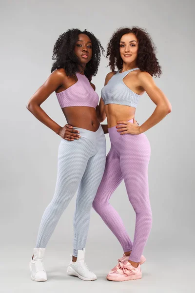 两个健身妇女在运动衫隔离灰色背景。体育与时尚概念与复制空间. — 图库照片