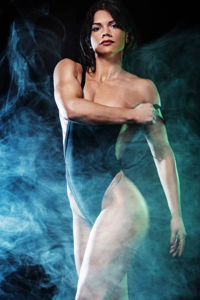 Έντονη αθλητική γυναίκα στο μπικίνι δείχνει τους μυς σε μαύρο φόντο. Η έννοια άθλημα — Φωτογραφία Αρχείου