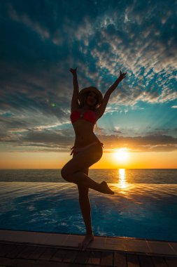 Yaz tatili. Güneş kadın bikini Yüzme Havuzu ve deniz günbatımı üzerinde zevk.