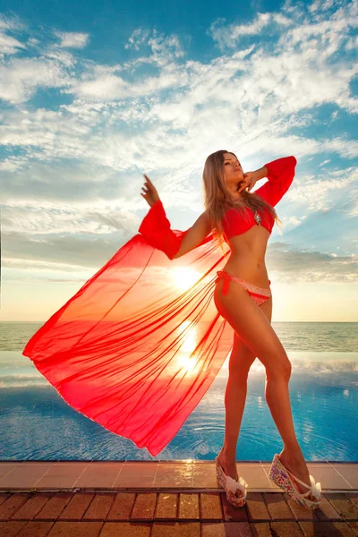 Vacances d'été. Silhouette de danseuse de beauté au coucher du soleil près de la piscine avec vue sur l'océan. Plage à la mer bleue . — Photo