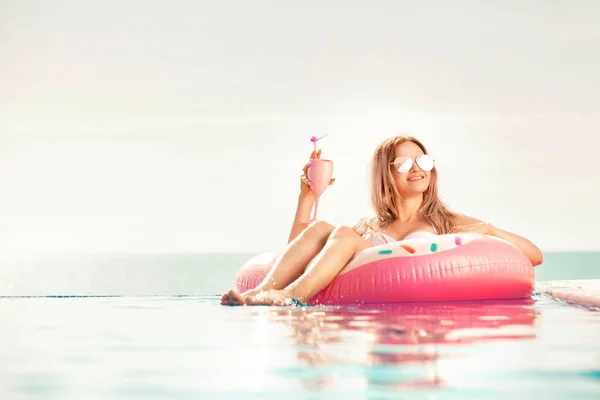 Zomervakantie. Vrouw in bikini op de opblaasbare donut matras in het zwembad van Spa. — Stockfoto