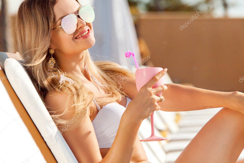 Young woman with coctail on the beach at summer