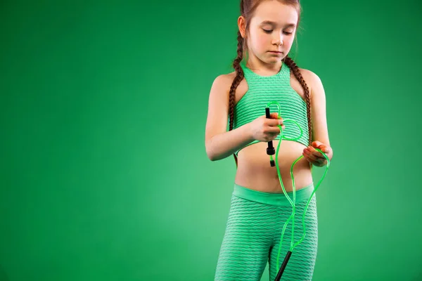 Spor kavram. Yeşil arka plan üzerinde Fitness egzersizleri yapıyor çocuk kız. — Stok fotoğraf