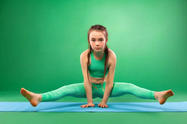Kid girl doing fitness exercises on green background — Stock Photo, Image