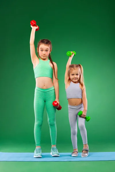 Niños niñas haciendo ejercicios de fitness sobre fondo verde juntos — Foto de Stock