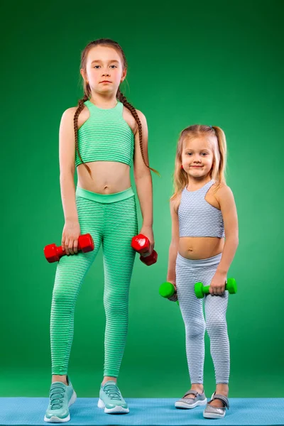 Crianças meninas fazendo exercícios de fitness no fundo verde juntos — Fotografia de Stock