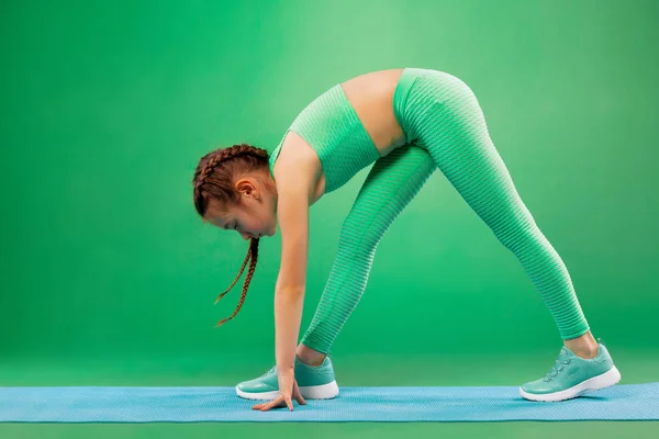 Gyerek lány csinál fitness gyakorlatok zöld háttér — Stock Fotó