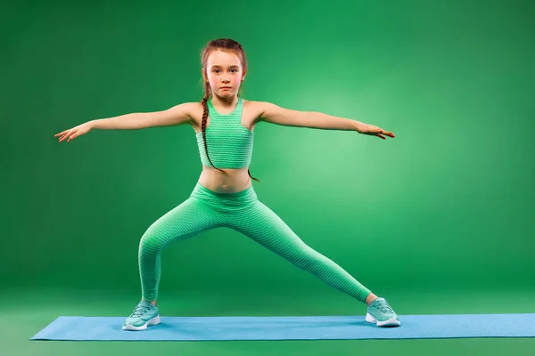 Девочка делает упражнения на зеленом фоне — стоковое фото