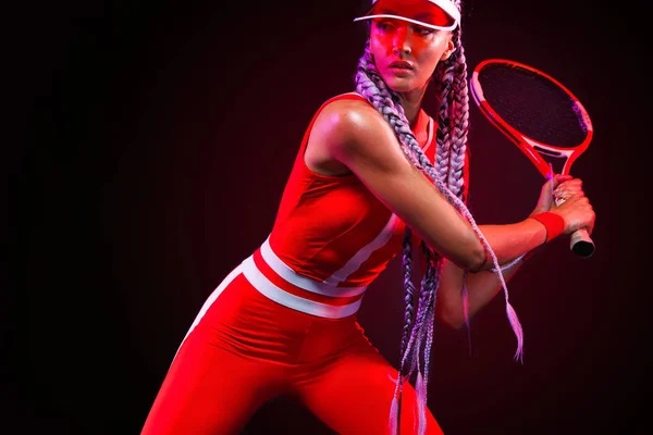 Joueur de tennis. Belle athlète femme avec raquette en costume rouge et chapeau isolé sur fond noir. Concept mode et sport . — Photo