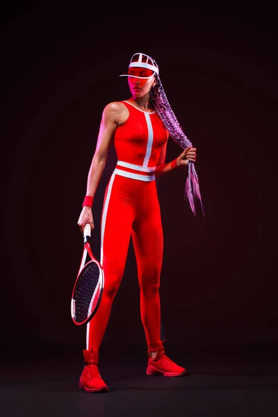 Tennis player. Beautiful woman athlete with racket in red costume and hat isolated on black background. Fashion and sport concept. — Stock Photo, Image