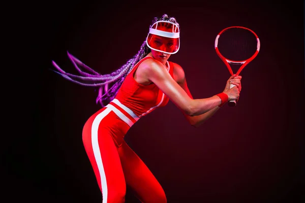 Tenista. Krásná žena sportovec s raketou v červený kostým a čepice izolované na černém pozadí. Móda a sport koncept. — Stock fotografie