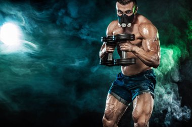 Kas Genç fitness spor eğitim maskeli adam. Egzersiz fitness salonunda dumbbell ile. Fitness beslenme reklamlar için kopya alanı.