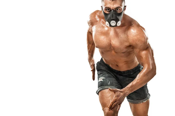 Brutal forte musculoso homem atlético fisiculturista bombeando os músculos em máscara de treinamento no fundo branco. Conceito de musculação treino. Espaço de cópia para anúncios de nutrição esportiva . — Fotografia de Stock