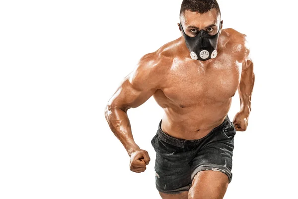 Brutal forte musculoso homem atlético fisiculturista bombeando os músculos em máscara de treinamento no fundo branco. Conceito de musculação treino. Espaço de cópia para anúncios de nutrição esportiva . — Fotografia de Stock
