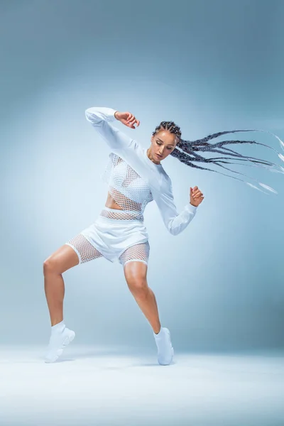 Приваблива збуджена танцівниця фітнесу в спортивному одязі, стрибки радості ізольовані на сірому фоні — стокове фото