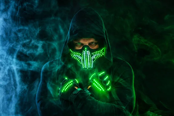 Mysterious man in black wear, neon mask and gloves. Character pastor or wizard in robe from the future. Assassin with strong face expression. Fantasy book or computer game cover concept. — Stock Photo, Image