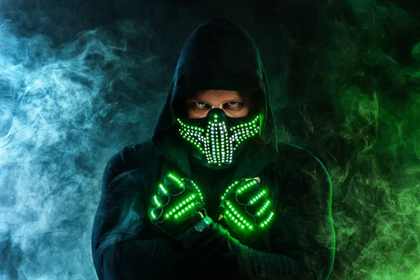 Mysterious man in black wear, neon mask and gloves. Character pastor or wizard in robe from the future. Assassin with strong face expression. Fantasy book or computer game cover concept. — Stock Photo, Image