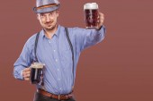 Portrét Oktoberfest muže v klobouku, na sobě tradiční bavorské oblečení slouží velký pivní korbele.