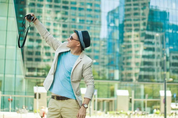 O homem faz selfie na cidade grande contra o fundo de arranha-céus. Viagem e conceito de estilo de vida . — Fotografia de Stock