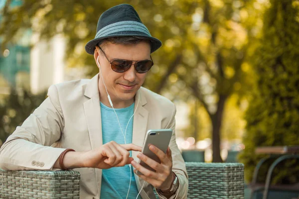 一个戴着帽子和墨镜的男人在电话旁微笑着公园旅行和生活方式的概念. — 图库照片