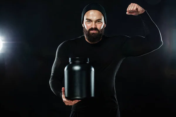 Feliz y saludable musculoso joven deportista fitness con un frasco de nutrición deportiva - proteína, ganadora y caseína —  Fotos de Stock