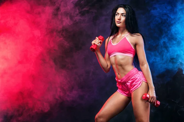 Atractiva joven atleta fitness mujer y culturista sosteniendo mancuerna. Espacio de copia para anuncios de nutrición fitness . — Foto de Stock