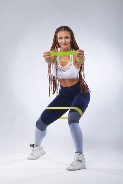 Kas Genç spor kadın atlet yerleştirmek. Egzersiz bantları veya genişletici içinde jimnastik salonu ile. Fitness beslenme reklamlar için kopya alanı.