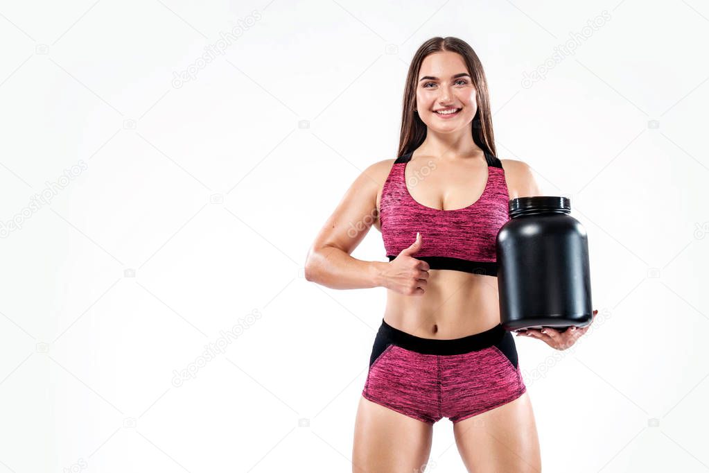 Happy and healthy muscular young fitness sports woman athlete with a jar of sports nutrition - protein, gainer and casein