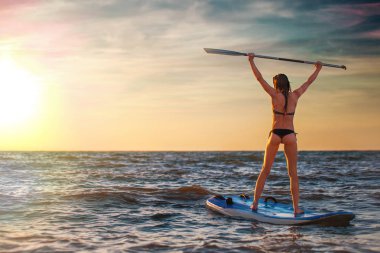 Gün batımında pratik SUP yoga, raket tahtada meditasyon kadın.