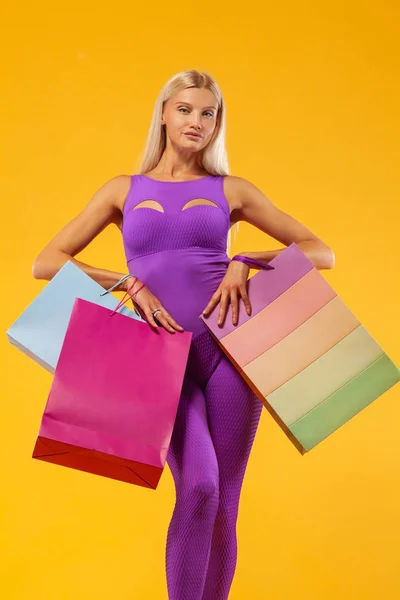 Μαύρη Παρασκευή πώληση αντίληψη για αθλητικών καταστημάτων. Ψώνια γυναίκα αθλητής κρατώντας την τσάντα χρώματος που απομονώνονται σε κίτρινο φόντο στις διακοπές — Φωτογραφία Αρχείου