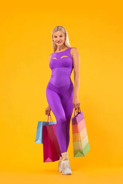 Venerdì nero concetto di vendita per negozi sportivi. Shopping donna atleta tenendo borsa di colore isolato su sfondo giallo in vacanza — Foto Stock