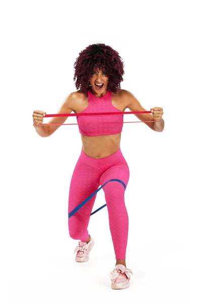 Muskulöse junge, fitte Sportlerin in pinkfarbener Sportbekleidung mit Bändern oder Expander im Fitnessstudio. Kopierraum für Fitness-Ernährungsanzeigen. — Stockfoto