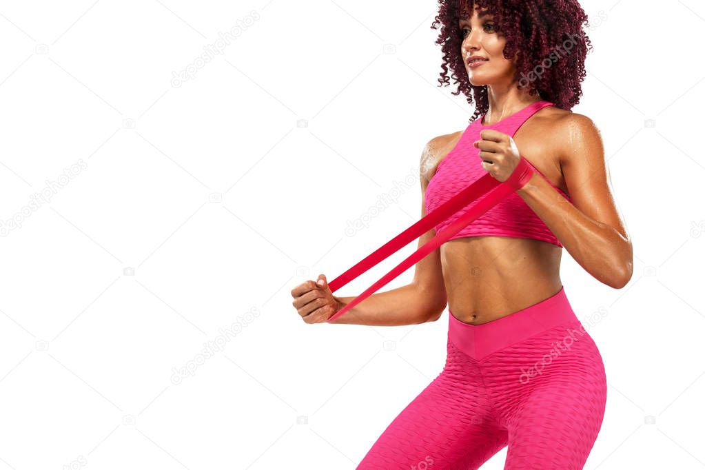 Muscular young fit sports woman athlete in pink sportswear with bands or expander in gym. Copy space for fitness nutrition ads.