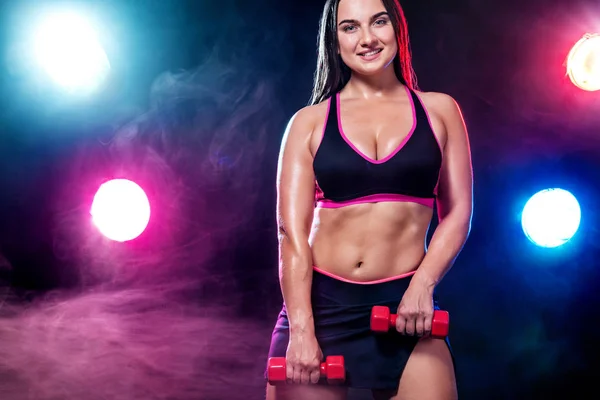 Méret plusz fitness nő sportoló és testépítő gazdaság súlyzó, fekete háttér, a fények és a füst. — Stock Fotó