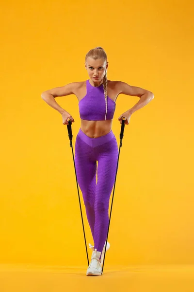 Mulher de fitness atleta e fisiculturista segurando expansor. Isolado sobre fundo amarelo . — Fotografia de Stock