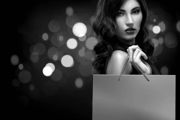 Natale o Venerdì nero concetto di vendita. Borsa shopping donna in possesso su sfondo scuro con bokeh in vacanza. BW foto . — Foto Stock