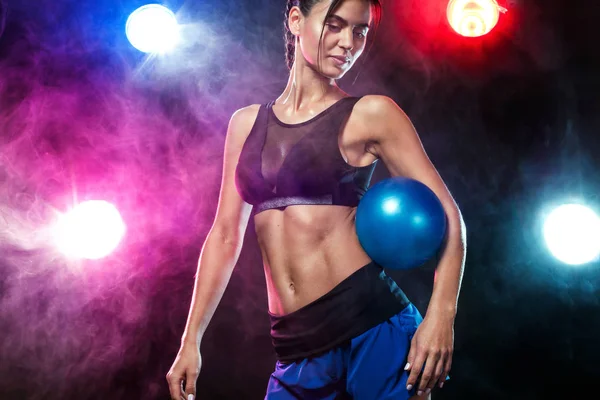 Γυμναστήριο όμορφη γυναίκα αθλητή και bodybuilder με το τέλειο σώμα κάνει trainging με φόντο ιατρική μπάλα. Εικόνα Αρχείου