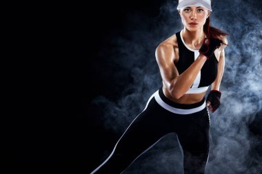 Güçlü atletik kadın sprinter, içinde spor giyim giymiş siyah arka plan üzerinde çalışan. Fitness ve spor motivasyon. Runner kavramı kopya alanı ile.