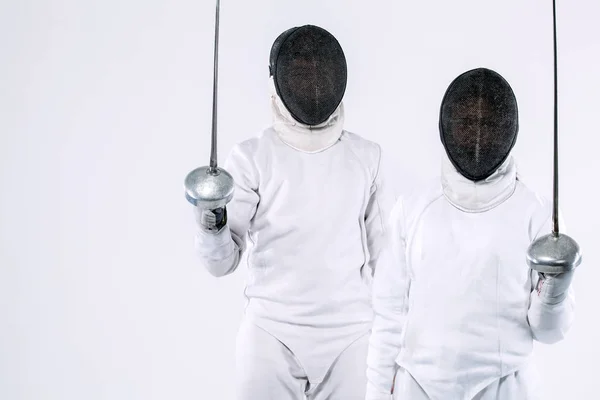 Twee jonge schermers atleten dragen van masker en witte schermen kostuum en houden van het zwaard. Geïsoleerd op witte achtergrond — Stockfoto