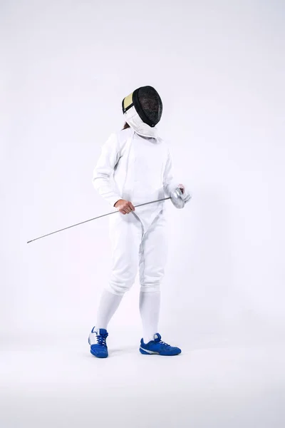 Αθλητής Ξιφασκίας φορώντας μάσκα και λευκό περίφραξη κοστούμι και κρατώντας το σπαθί. Απομονωμένα σε λευκό φόντο — Φωτογραφία Αρχείου