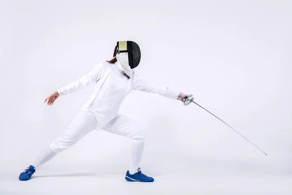 Mladý šermíř sportovec na sobě masku a bílá oplocení kostým. drží meč. Izolované na bílém pozadí — Stock fotografie