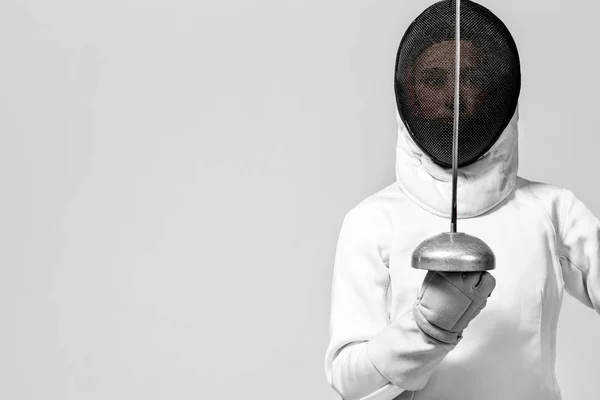 Mladý šermíř sportovec na sobě kostým oplocení držící meč a masku. Izolované na bílém pozadí — Stock fotografie