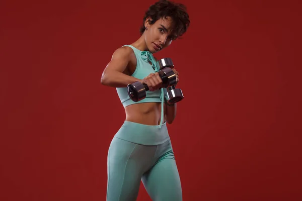 Fitness y motivación deportiva.. Fuerte y en forma atlética, mujer con tatuaje posando sobre fondo rojo en ropa deportiva . — Foto de Stock